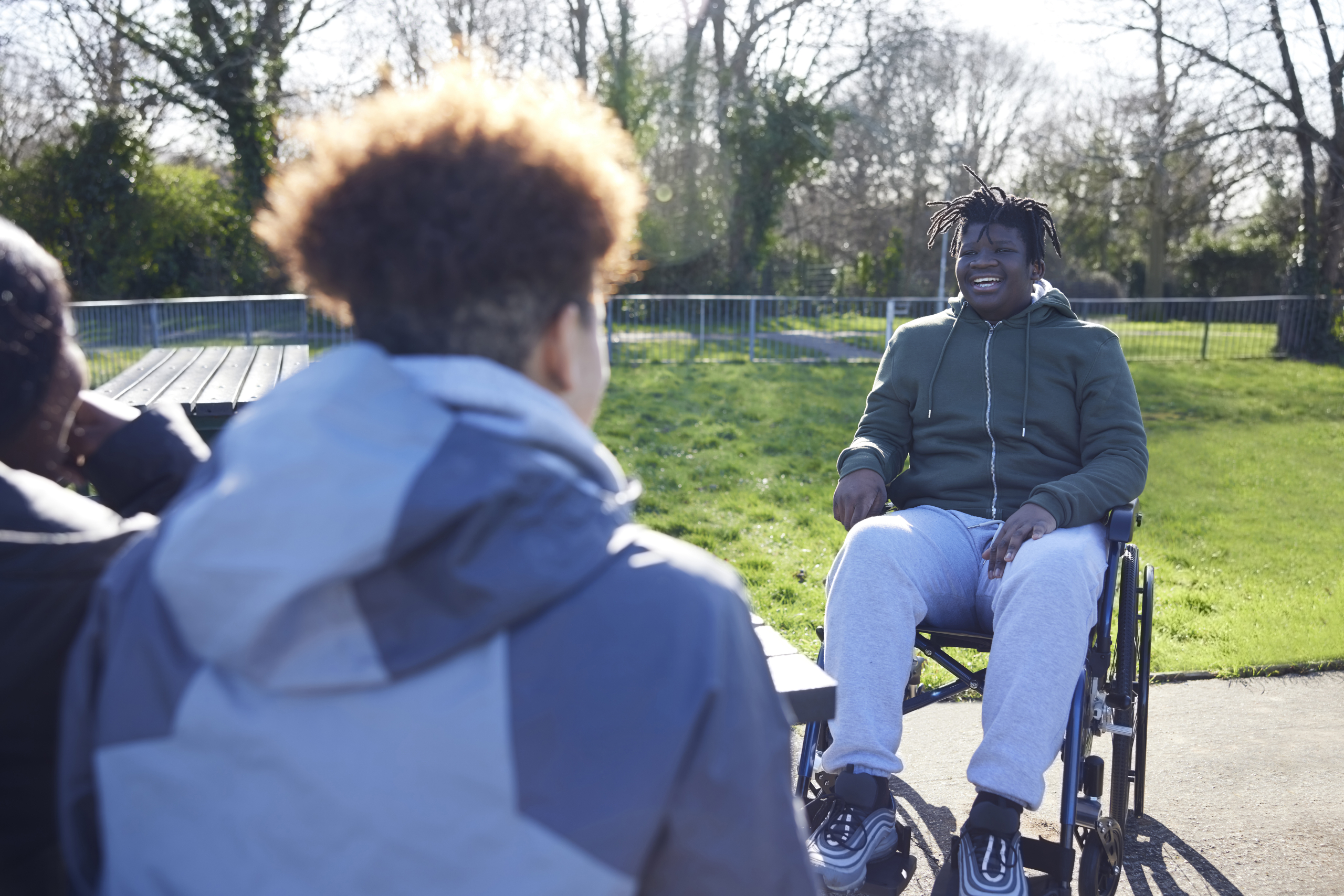 Teenage Boy In Wheelchair Hanging Out Talking And Laughing With